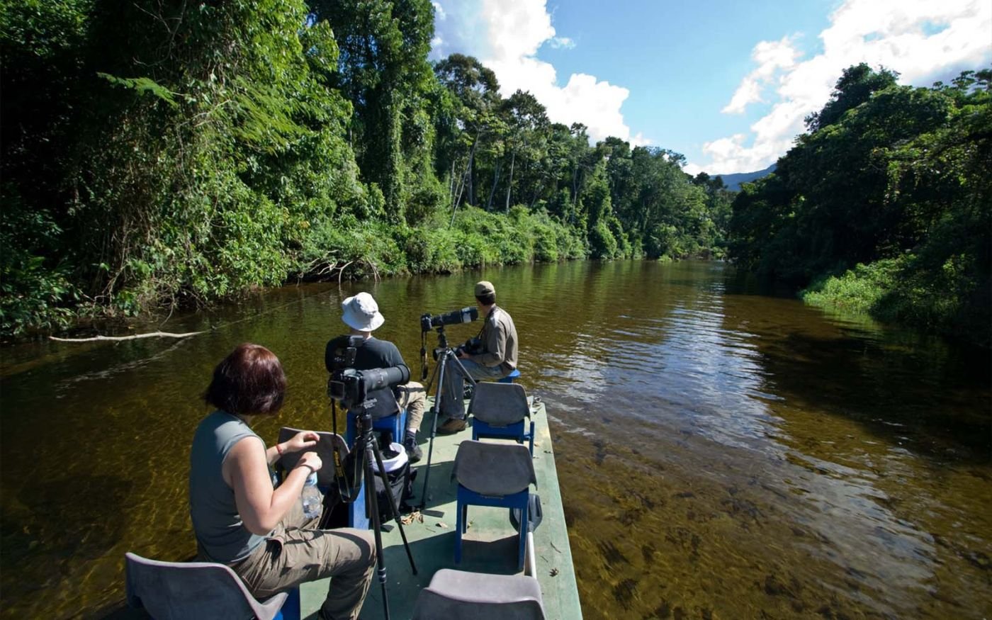 Grupo de fotógrafos em um barco observando aves no Rio Itamambuca