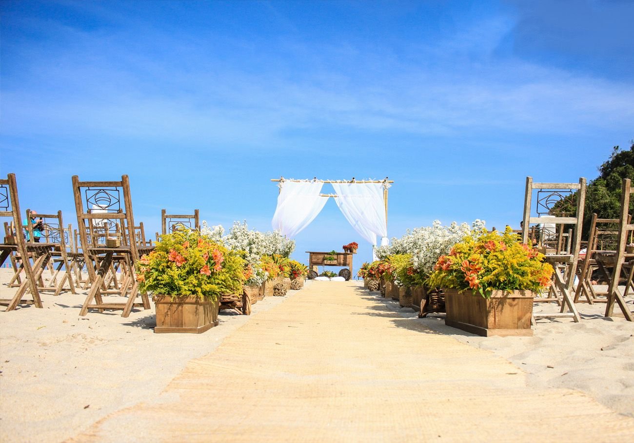 Casamento na areia da praia com altar ao centro e cadeiras dispostas nos dois lados